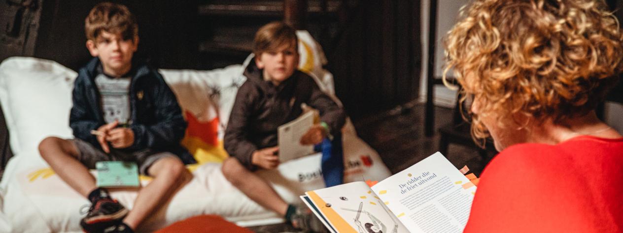 een dame leest voor aan twee geïnteresseerde kinderen in het Museum Plantin-Moretus