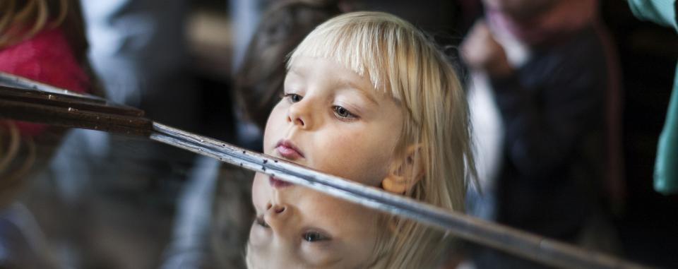 meisje kijkt in toonkast, dat lukt - door haar grootte - net