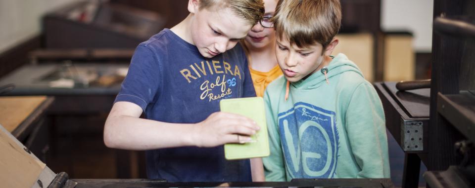 kinderen aan de drukpers tijdens een workshop