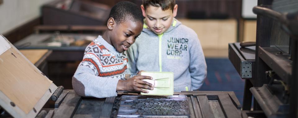 twee jongens aan de drukpers tijdens een workshop