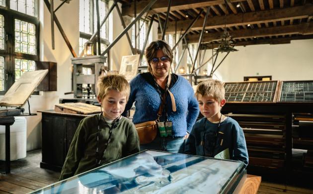 Twee kinderen met een ouder in de drukkerij