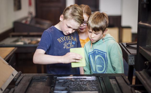 kinderen aan de drukpers tijdens een workshop